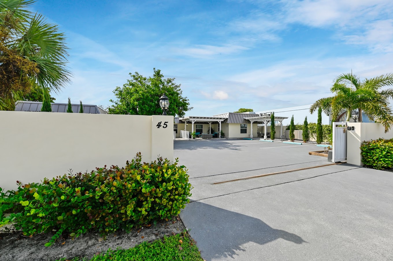 xterior view with white wall labeled 45, gated entry, and greenery.