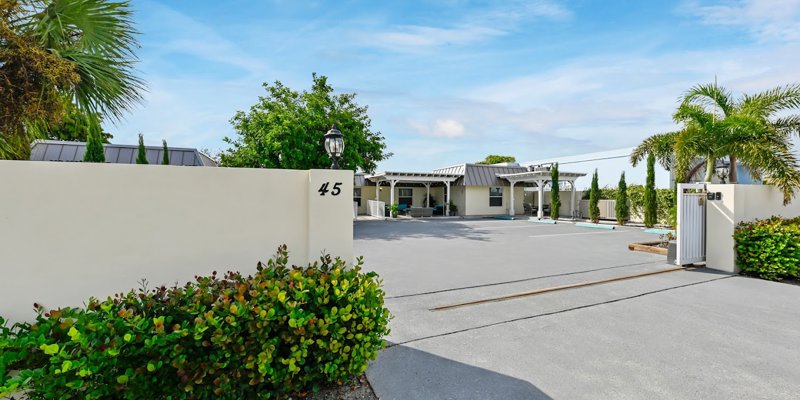  A modern, peaceful property with a gated entrance, lush greenery, and a bright, open courtyard, creating a welcoming and serene atmosphere.