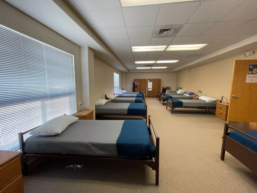 Neat dorm room with several single beds and nightstands