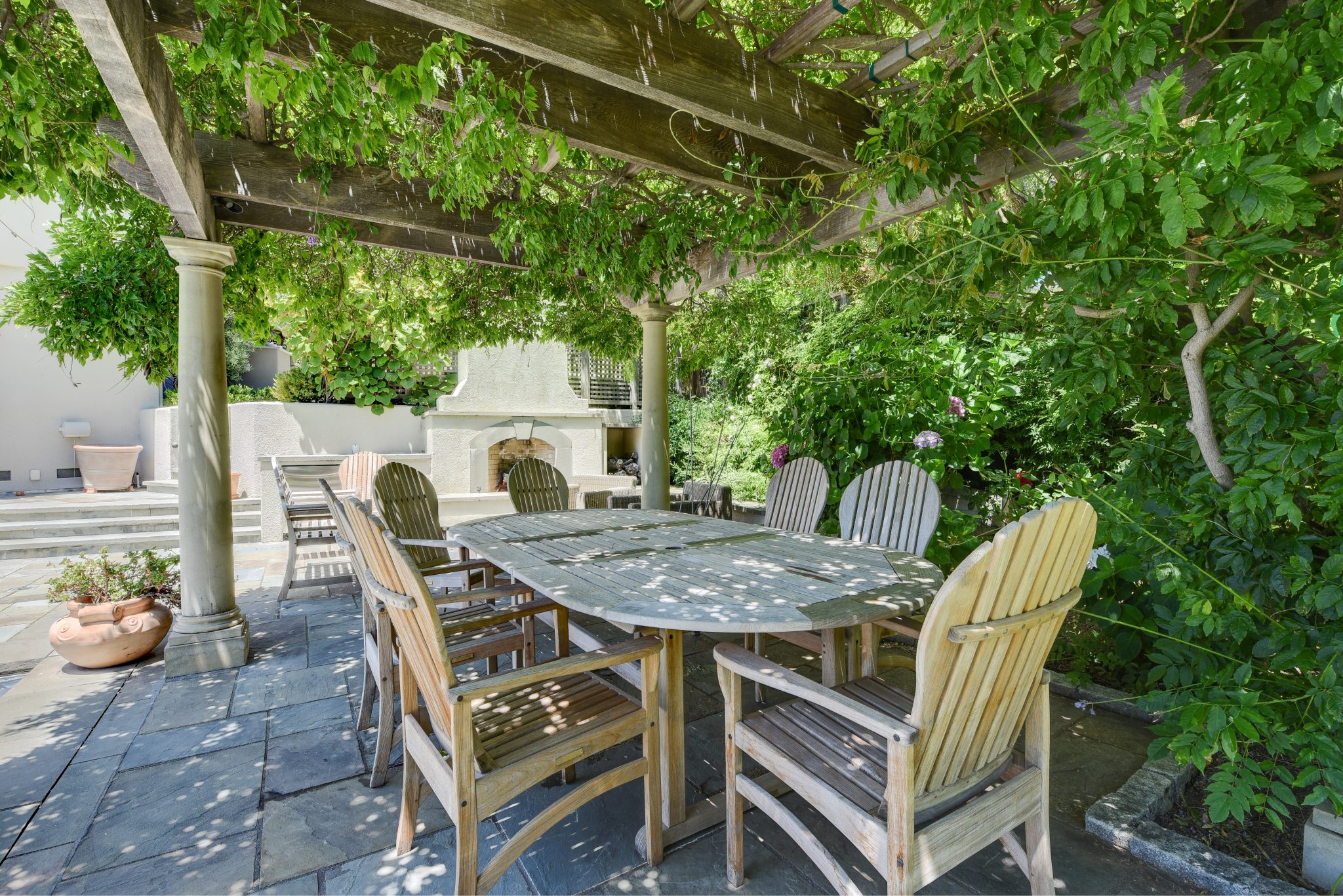 Outdoor patio dining area shaded by greenery.