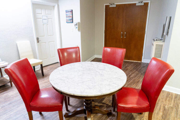 Round dining table with red chairs in shared dining area