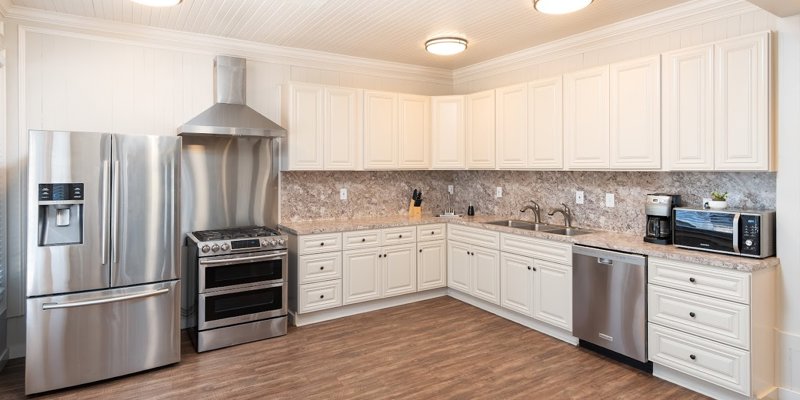 A spacious, modern kitchen with stainless steel appliances, white cabinets, and a large countertop, offering a clean and inviting space for cooking.