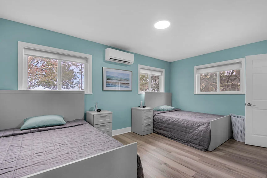 Shared bedroom with two beds, nightstands, and windows