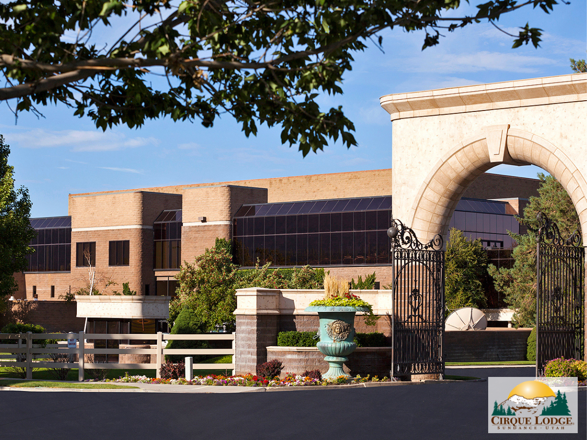 rick building and gated entry surrounded by green landscaping