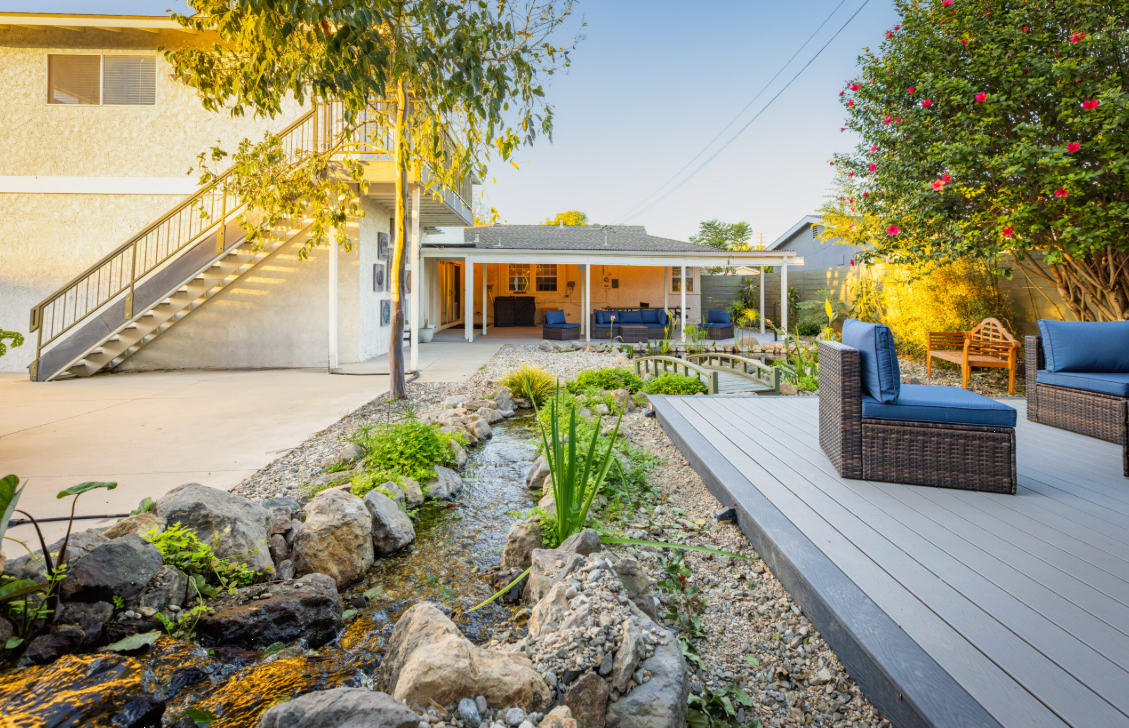 Backyard with patio seating and landscaped stream