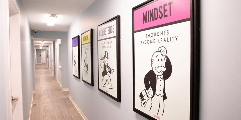 A well-lit hallway featuring motivational artwork with positive messages like "Mindset" and "Persistence," creating an encouraging atmosphere.