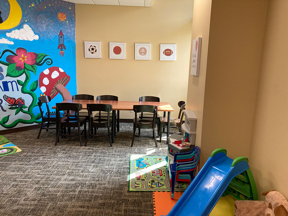 Playroom with small table, chairs, and colorful wall mural