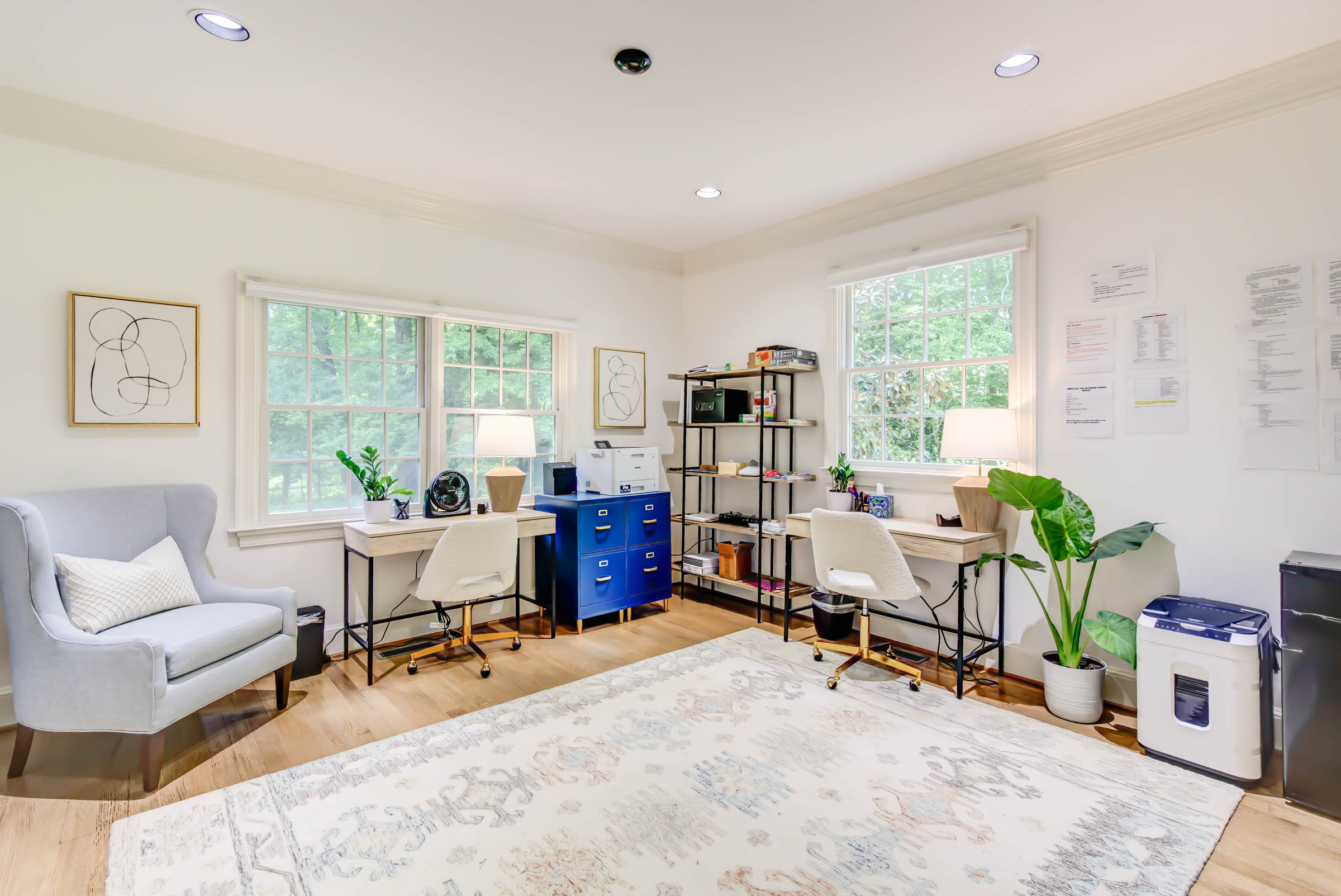 Office with desks, chairs, printer, and windows.