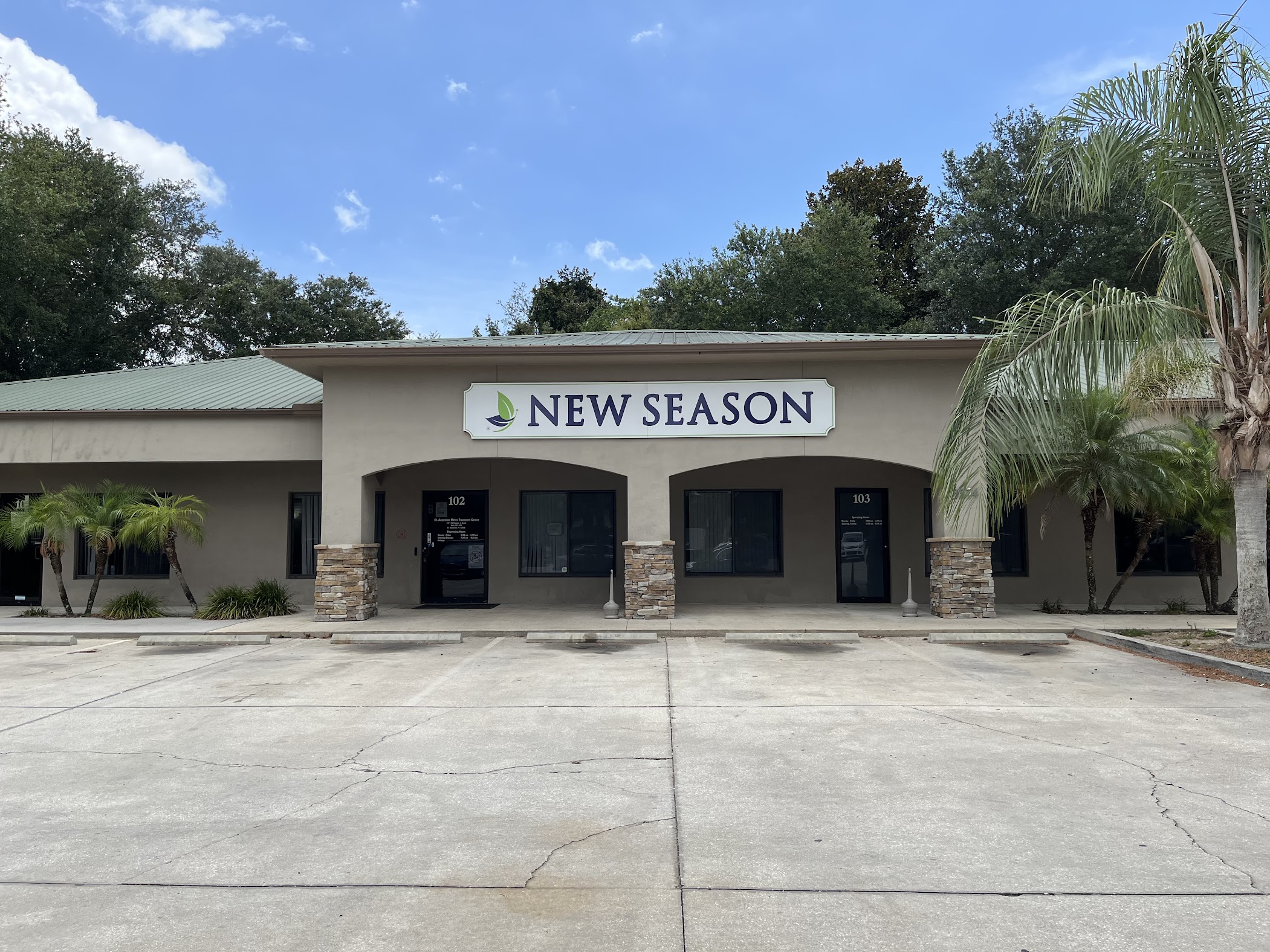 Front view of New Season building with palm trees and sign