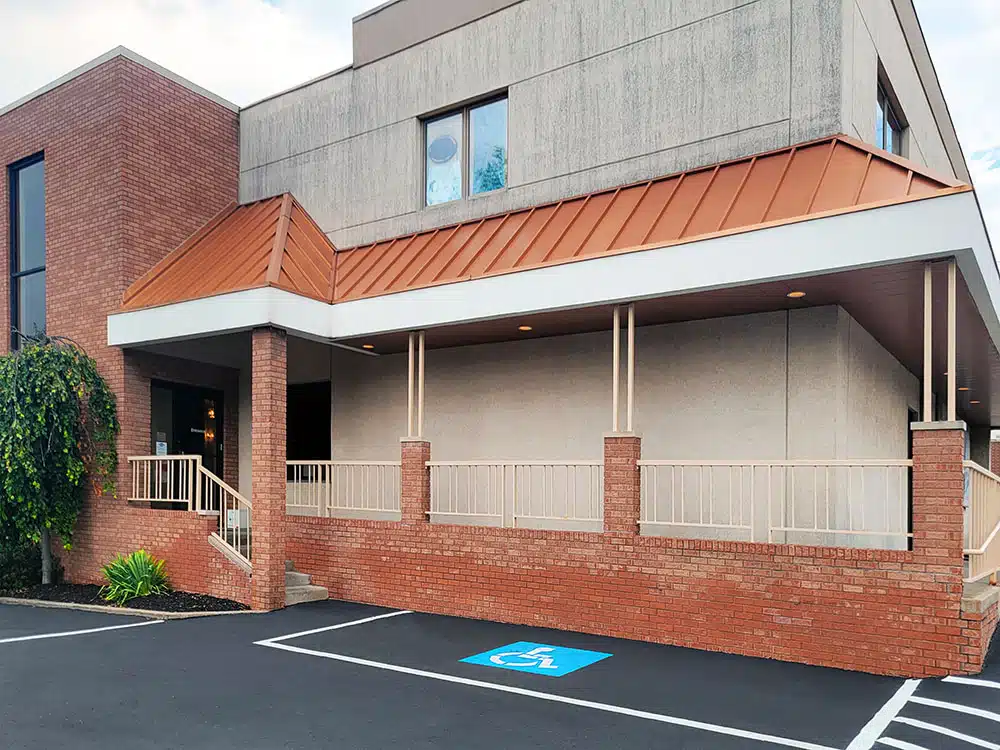 Exterior of treatment center building with brick facade, covered entrance, and accessible parking space