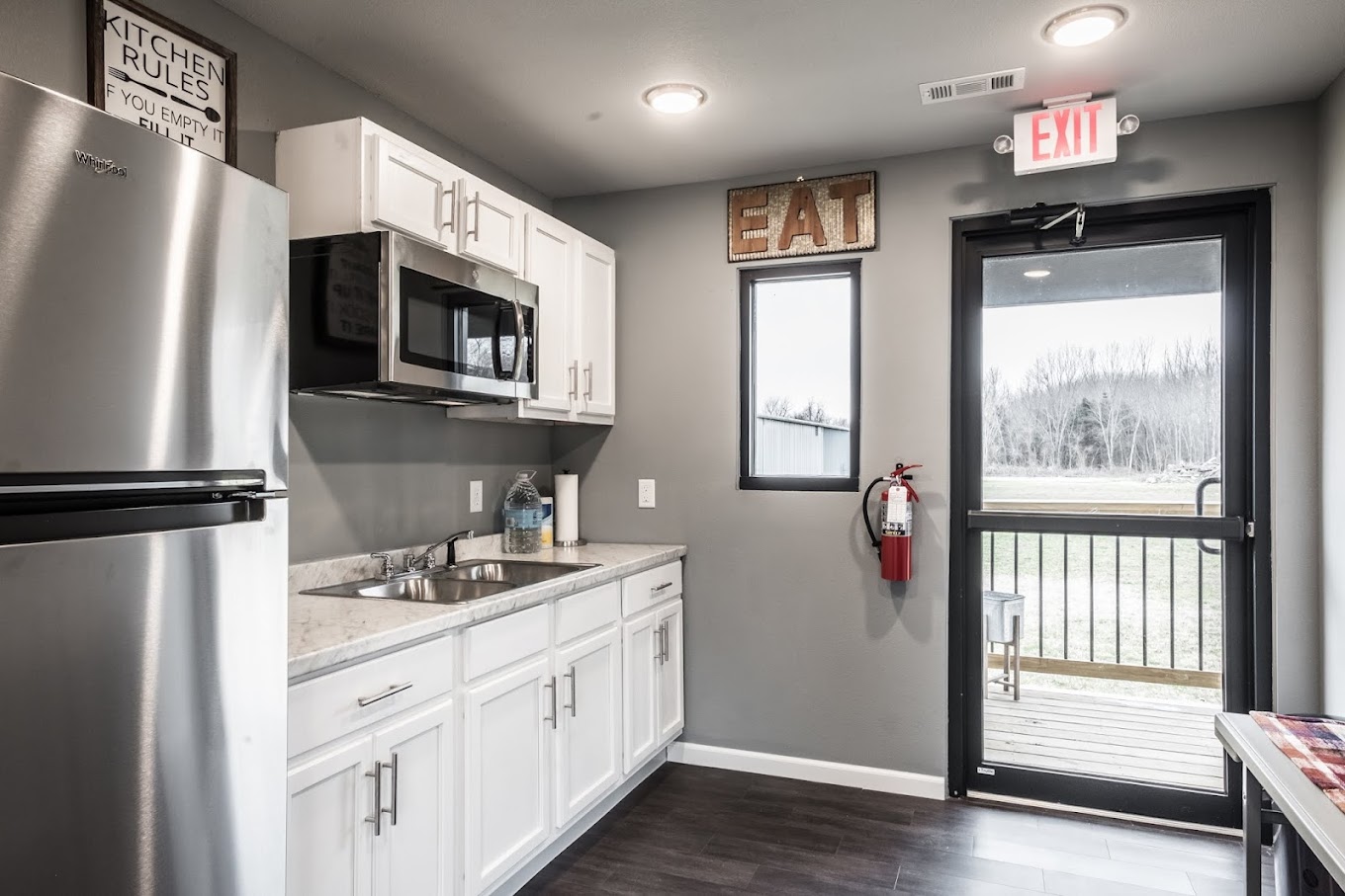 Compact kitchenette with white cabinets and stainless appliances