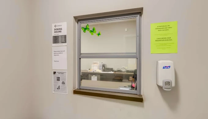 Dosing window with posted hours and hand sanitizer