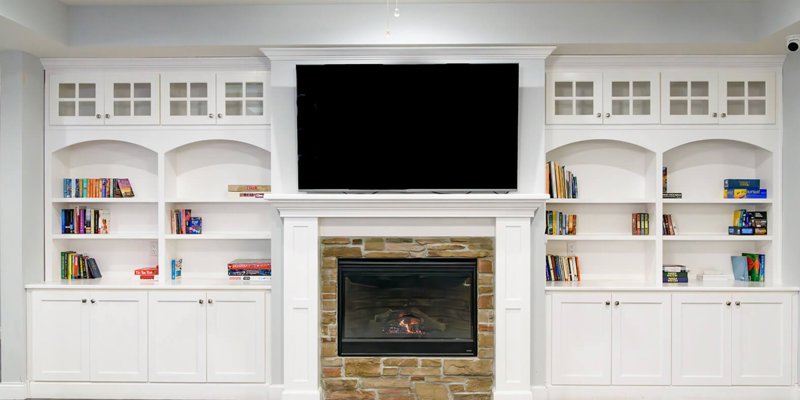 Cozy living area with a stone fireplace, built-in shelves filled with books and games, and a large TV, offering a relaxing atmosphere.