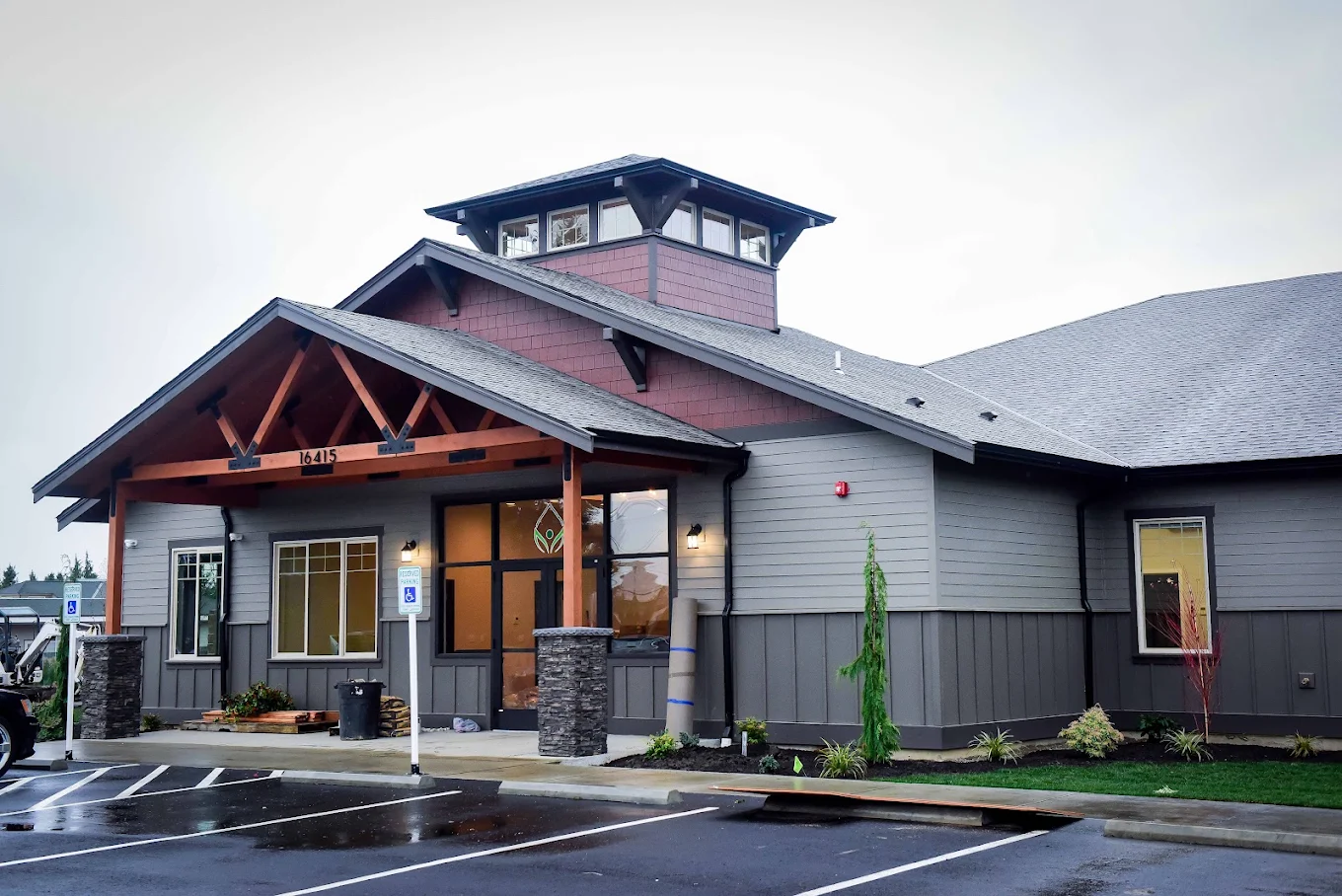 Modern facility entrance with covered drop-off and parking lot