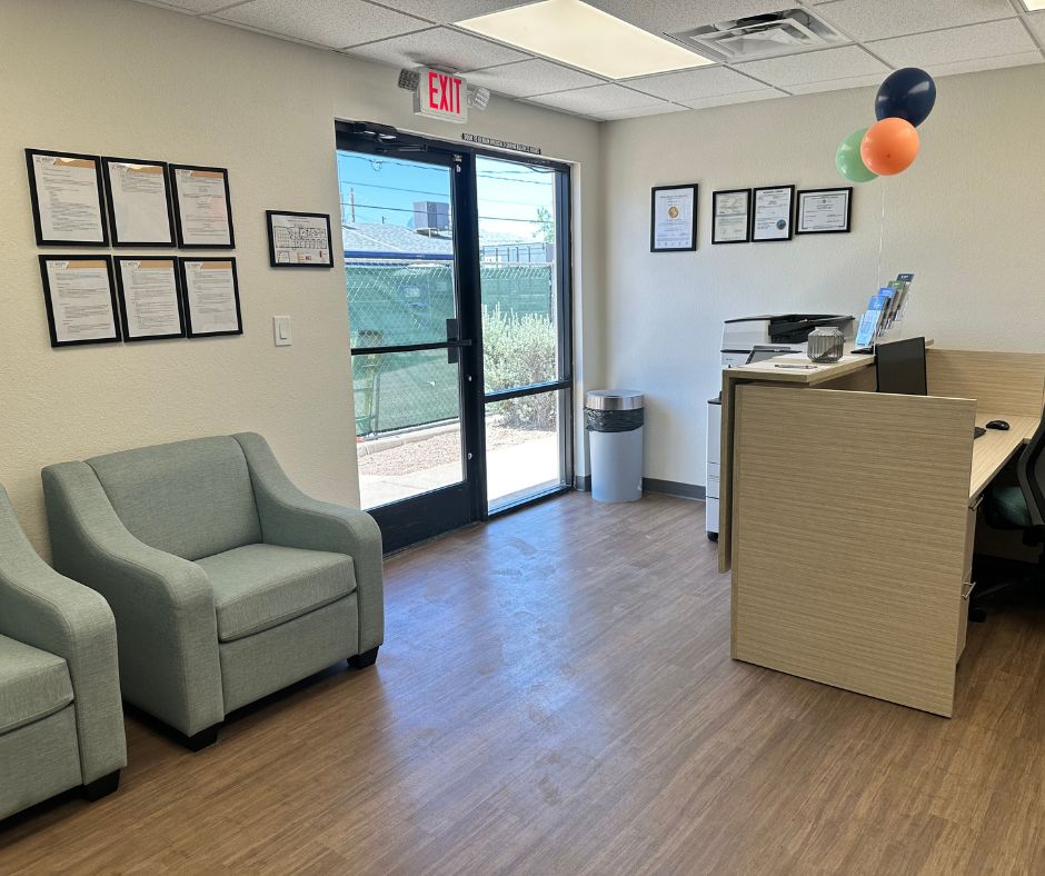 A small office with a desk, chairs, and framed certificates on the wall.