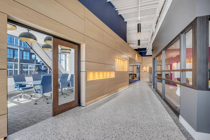 Hallway featuring a light wood accent wall and large conference room.