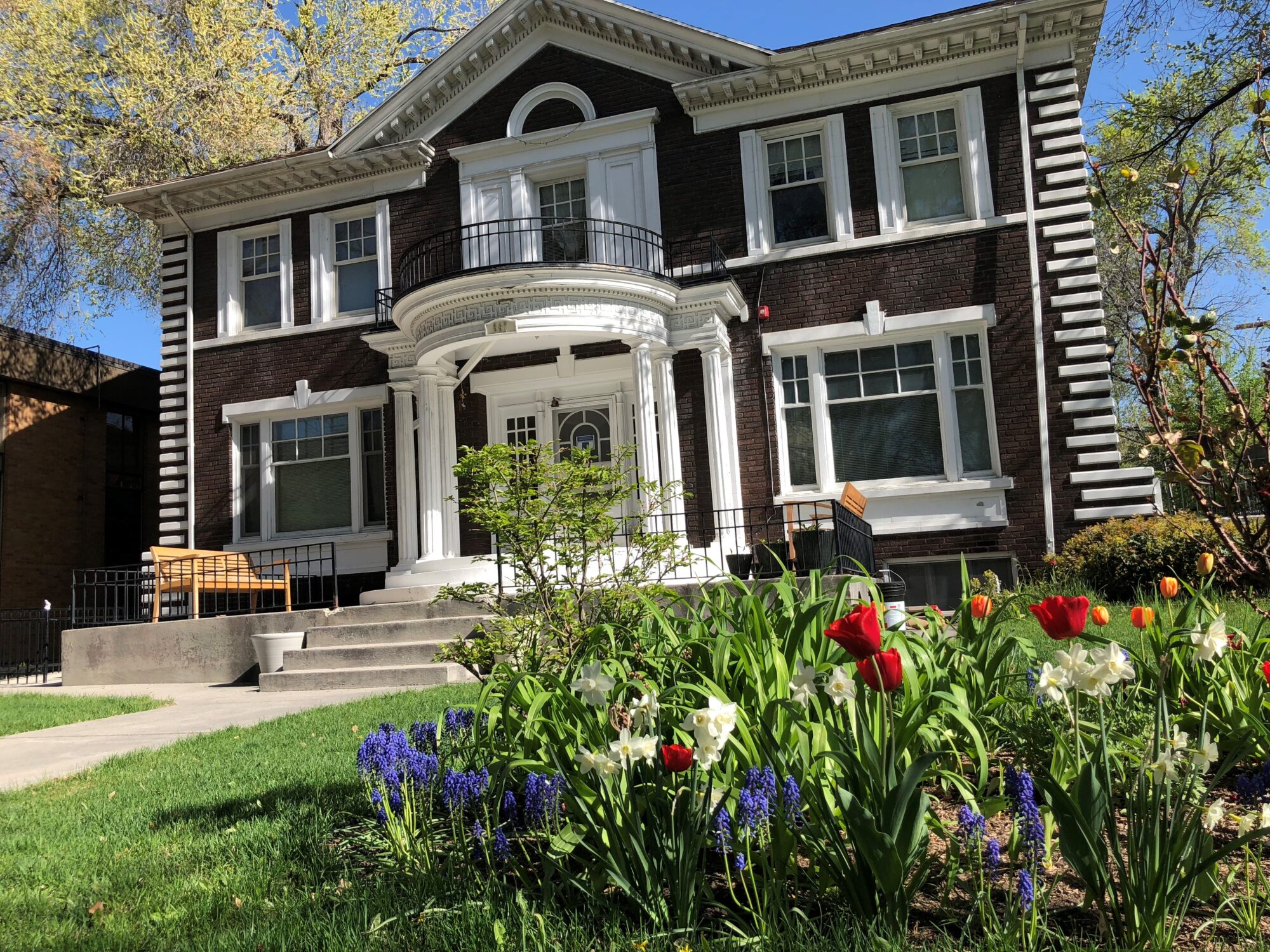 Historic brick home with flowers and bright green lawn