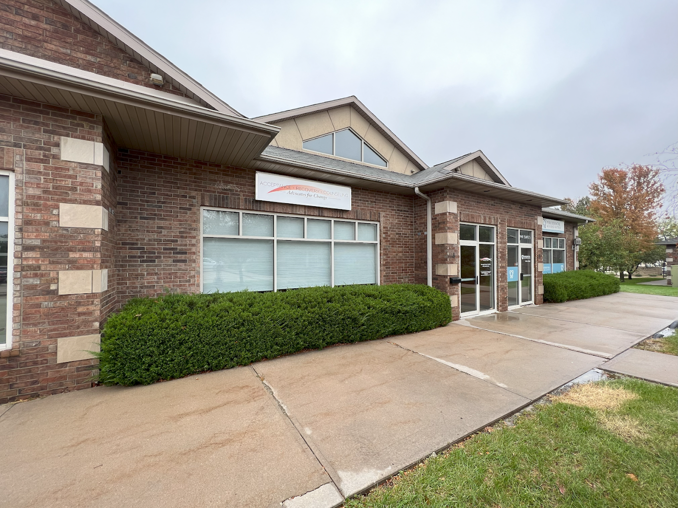 Brick rehab facility with large windows and trimmed hedges