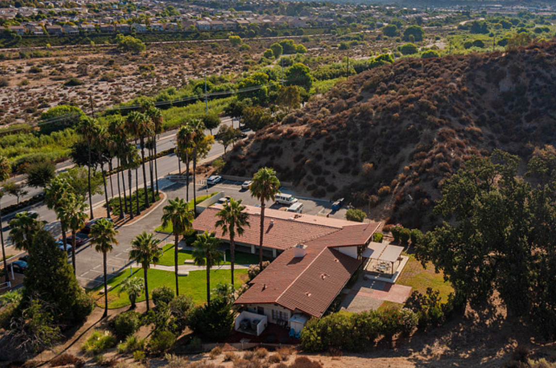 Rehab facility with red roof and palm trees from above.