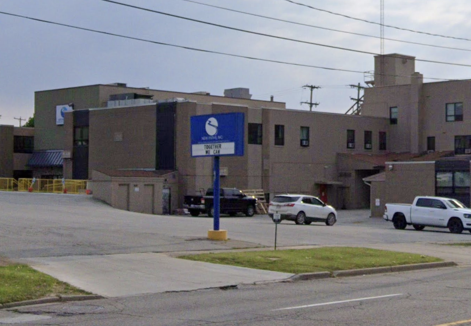 Multi-story treatment facility with blue sign and parking lot