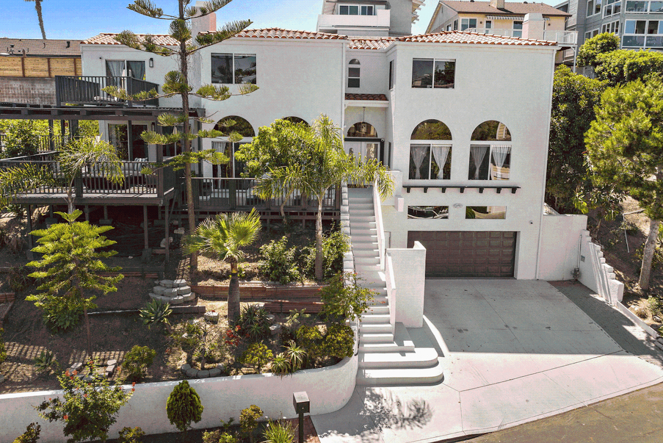 White multi-level residence with decks and landscaped grounds