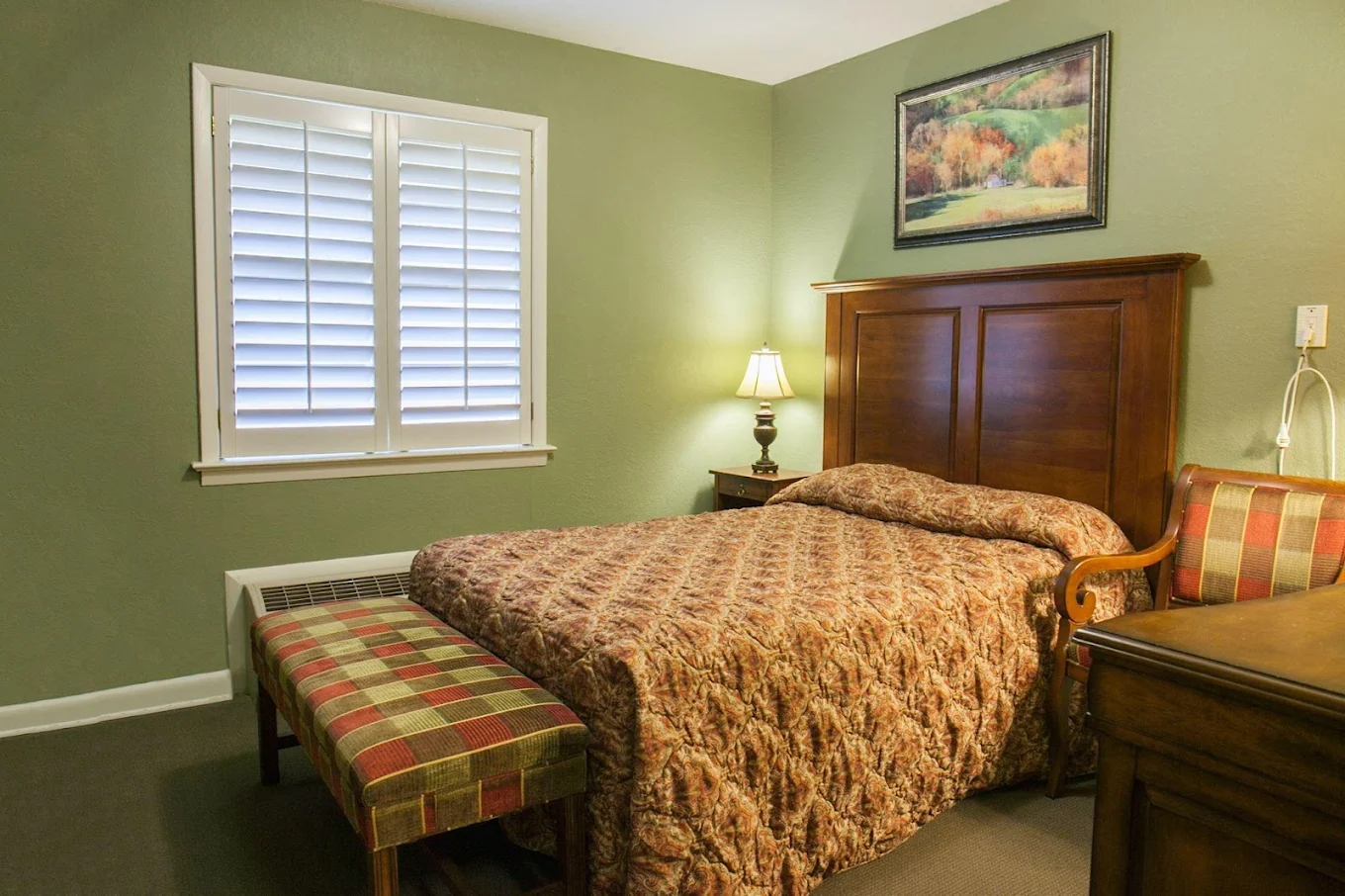 Private bedroom with bed, lamp, and green walls
