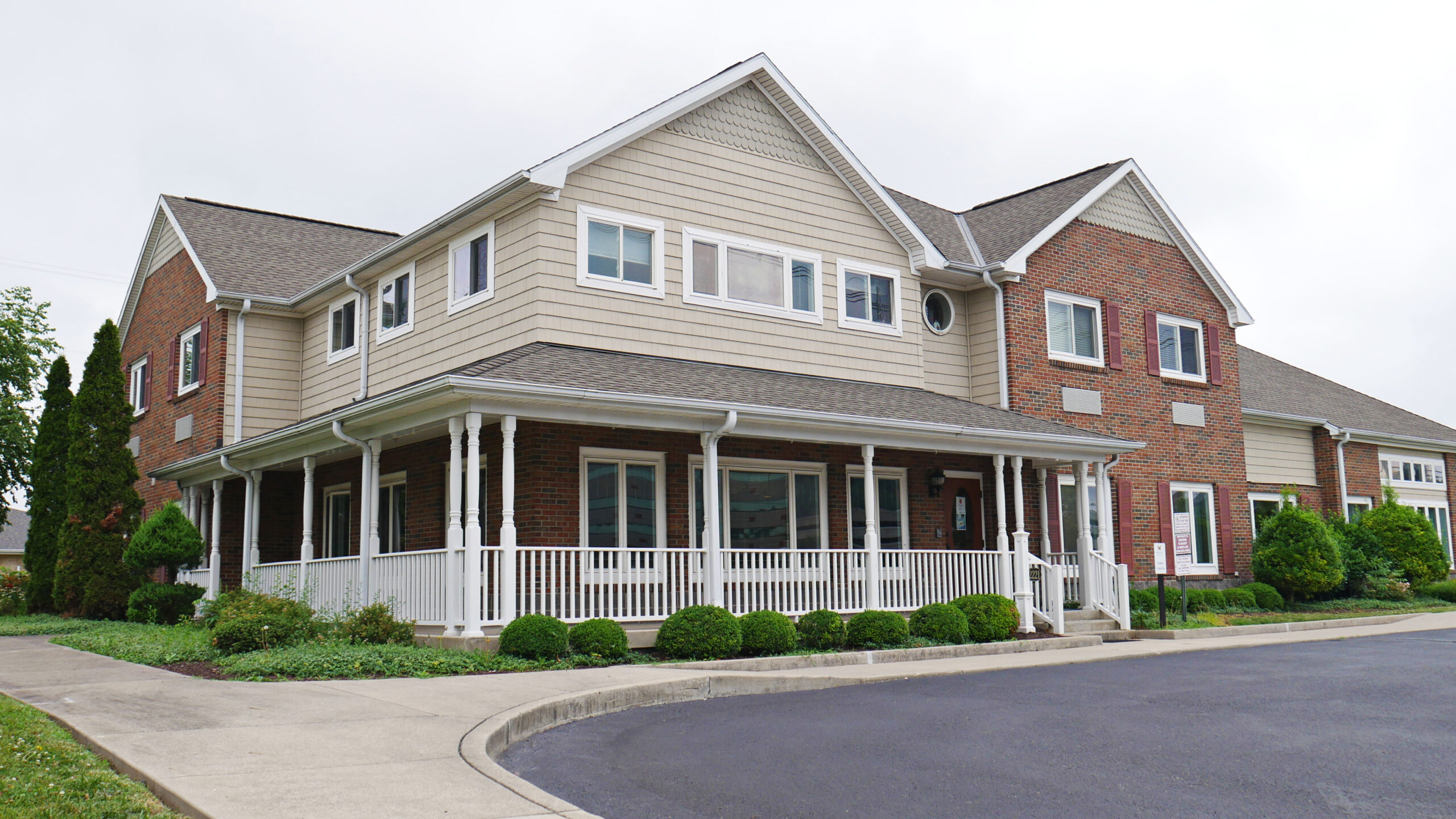 Two-story brick and siding rehab facility with covered front porch