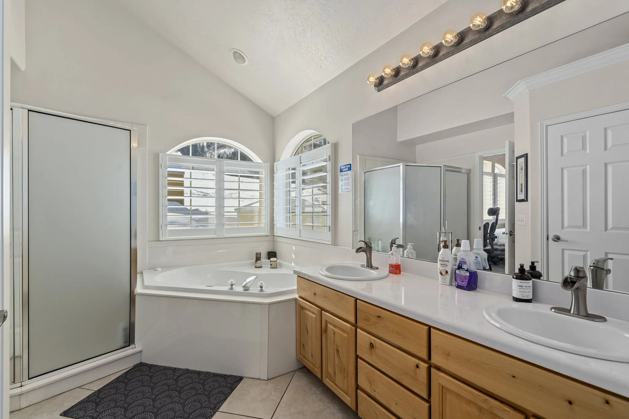 Bright bathroom with tub, dual sinks, and shower