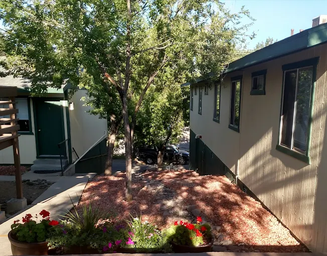 Walkway between housing units with trees, flowers, and landscaped surroundings.