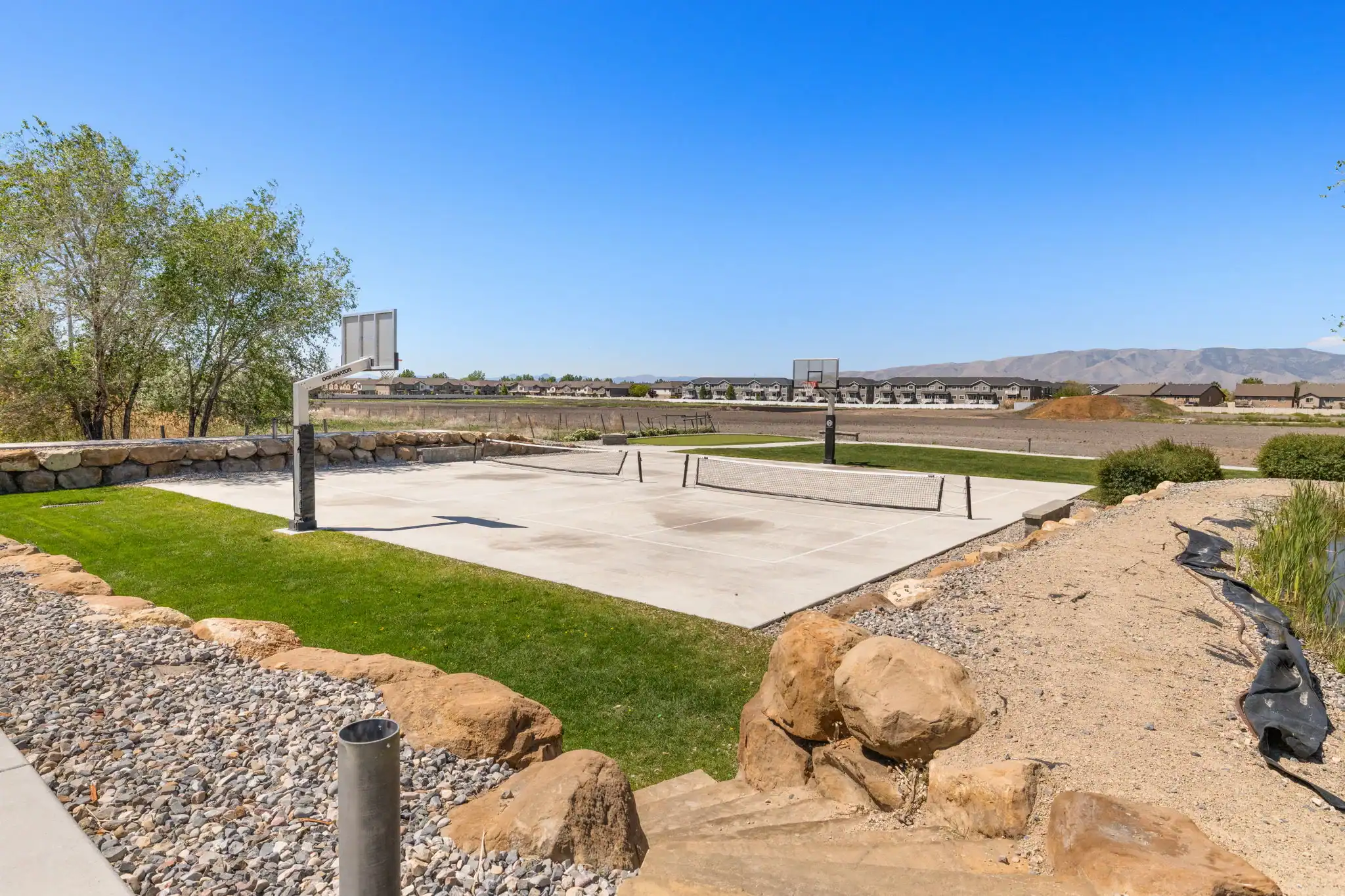 Outdoor sports court with basketball hoops and pickleball net