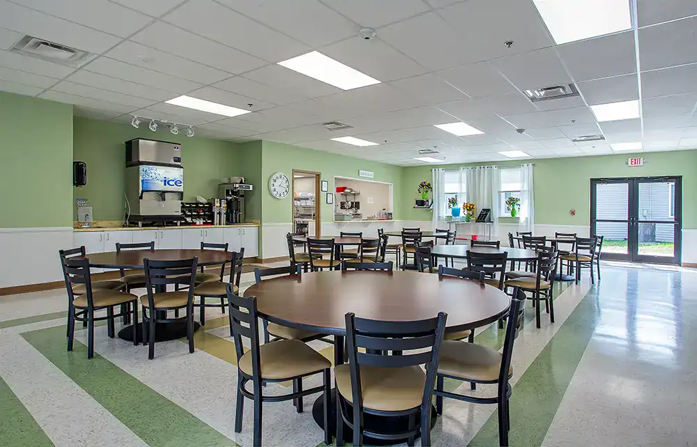Cafeteria with round tables, chairs, and beverage station