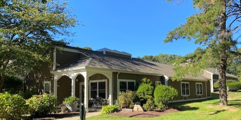 A charming building surrounded by lush greenery and trees, offering a peaceful and welcoming environment under a bright blue sky.