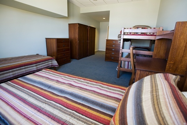 Bright shared bedroom with striped bedding and wood furniture