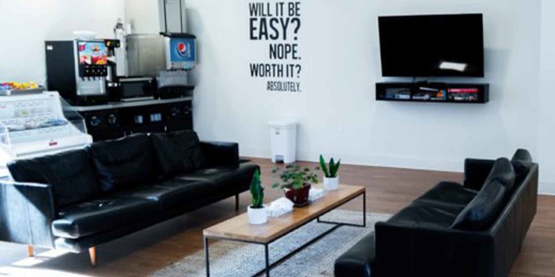  Modern lounge area with black leather sofas, a wooden coffee table, a TV, and motivational wall art, creating a cozy space to relax.