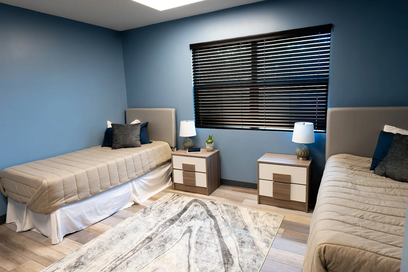 Two twin beds with blue walls and wood nightstands