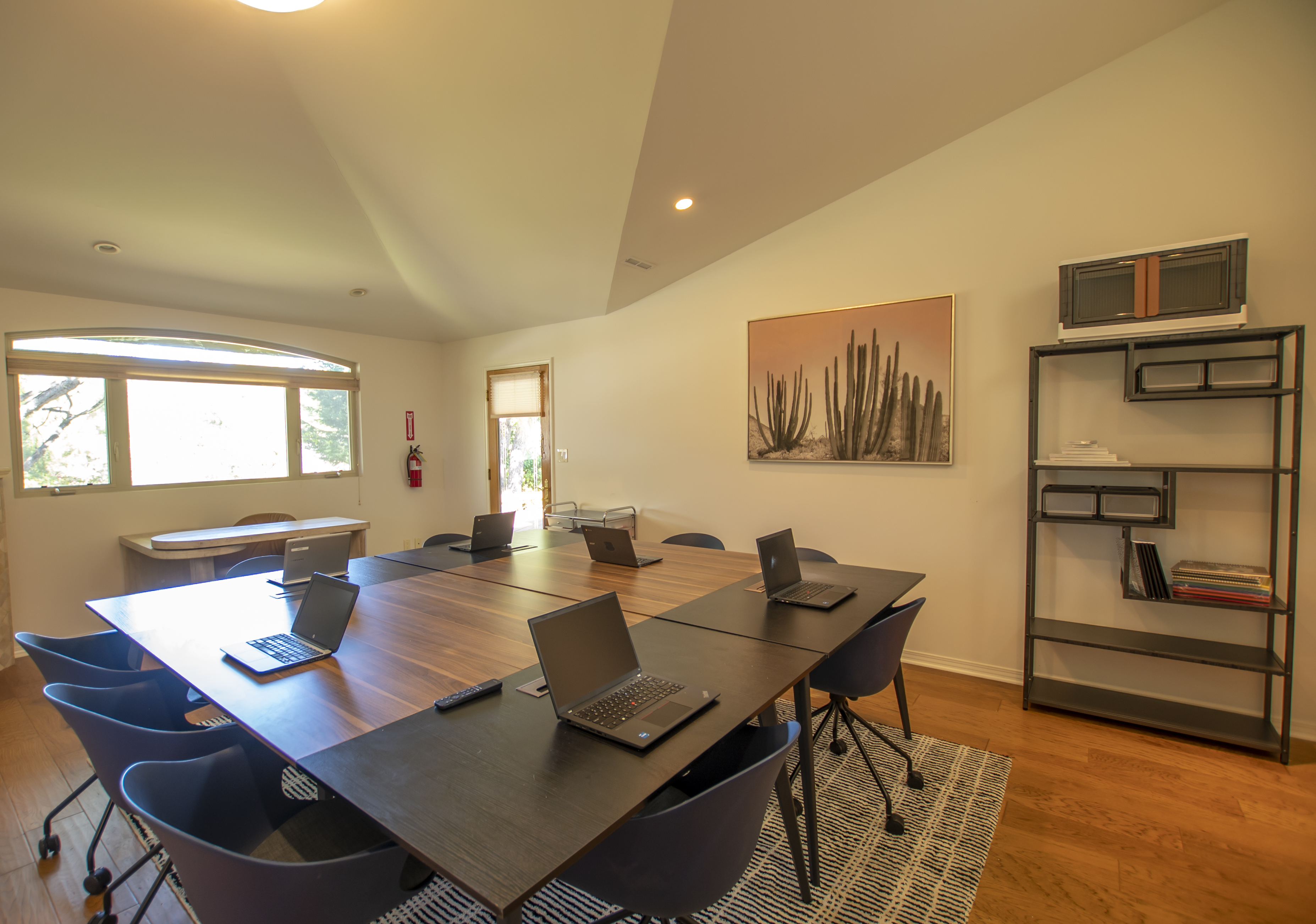 A meeting room with a long table, laptops, and a minimalist setup.