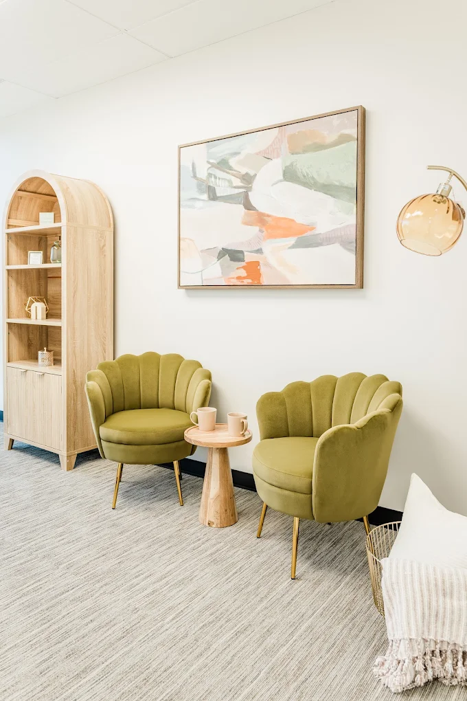 Modern waiting area with two green chairs and side table