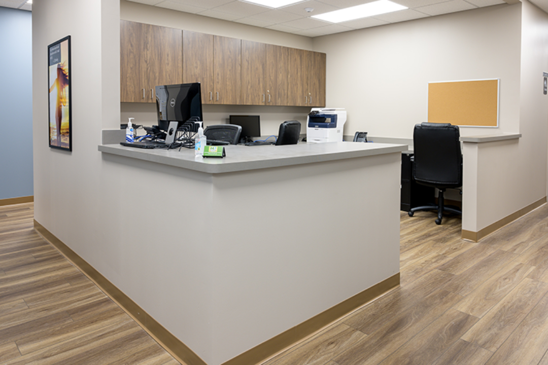 Nurses station with wraparound counter, computers, printer, and overhead cabinets