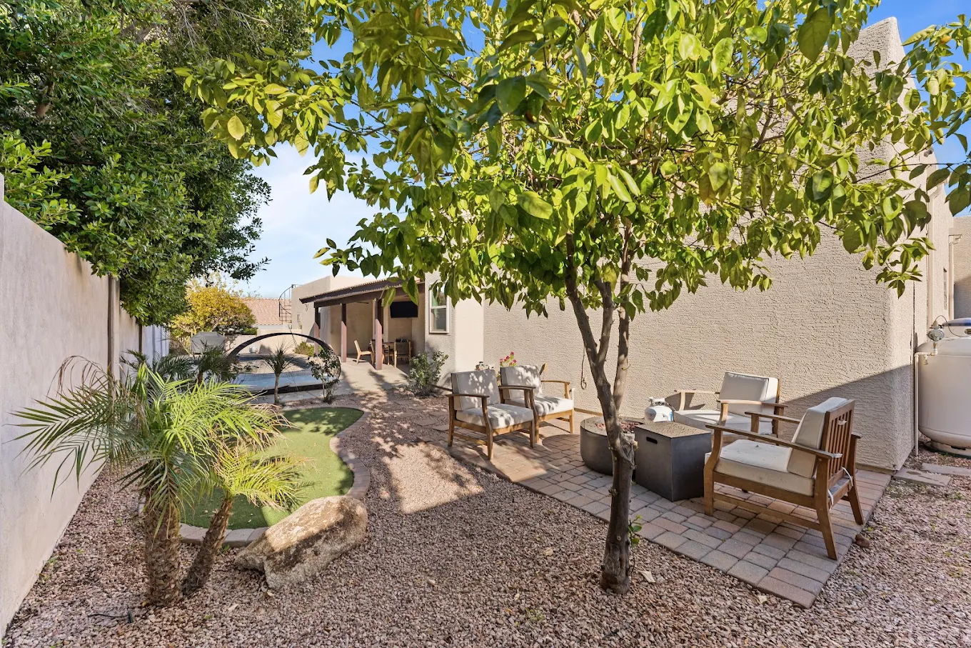 Shaded backyard seating area with chairs and landscaping