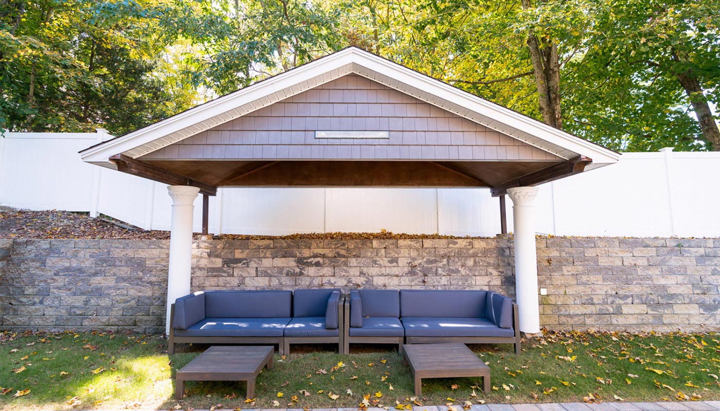 Covered outdoor lounge with cushioned seating and tables.