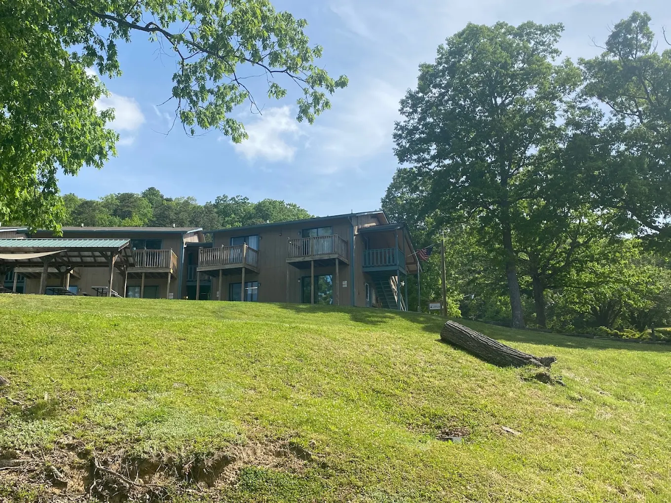 Residential building on a grassy hillside surrounded by mature trees
