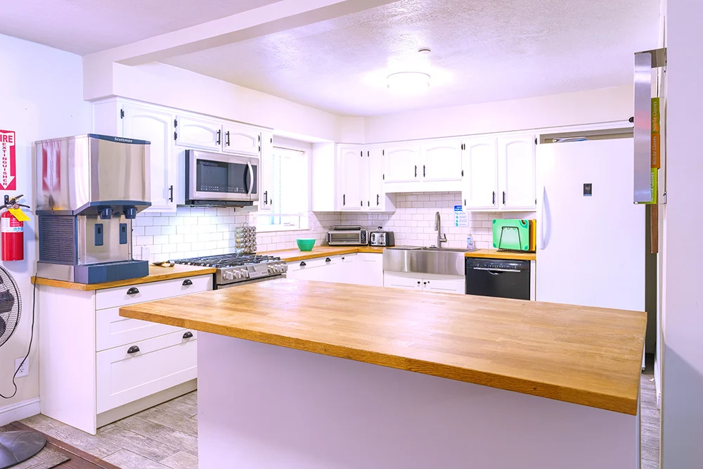 Clean kitchen with island, stove, and white cabinets