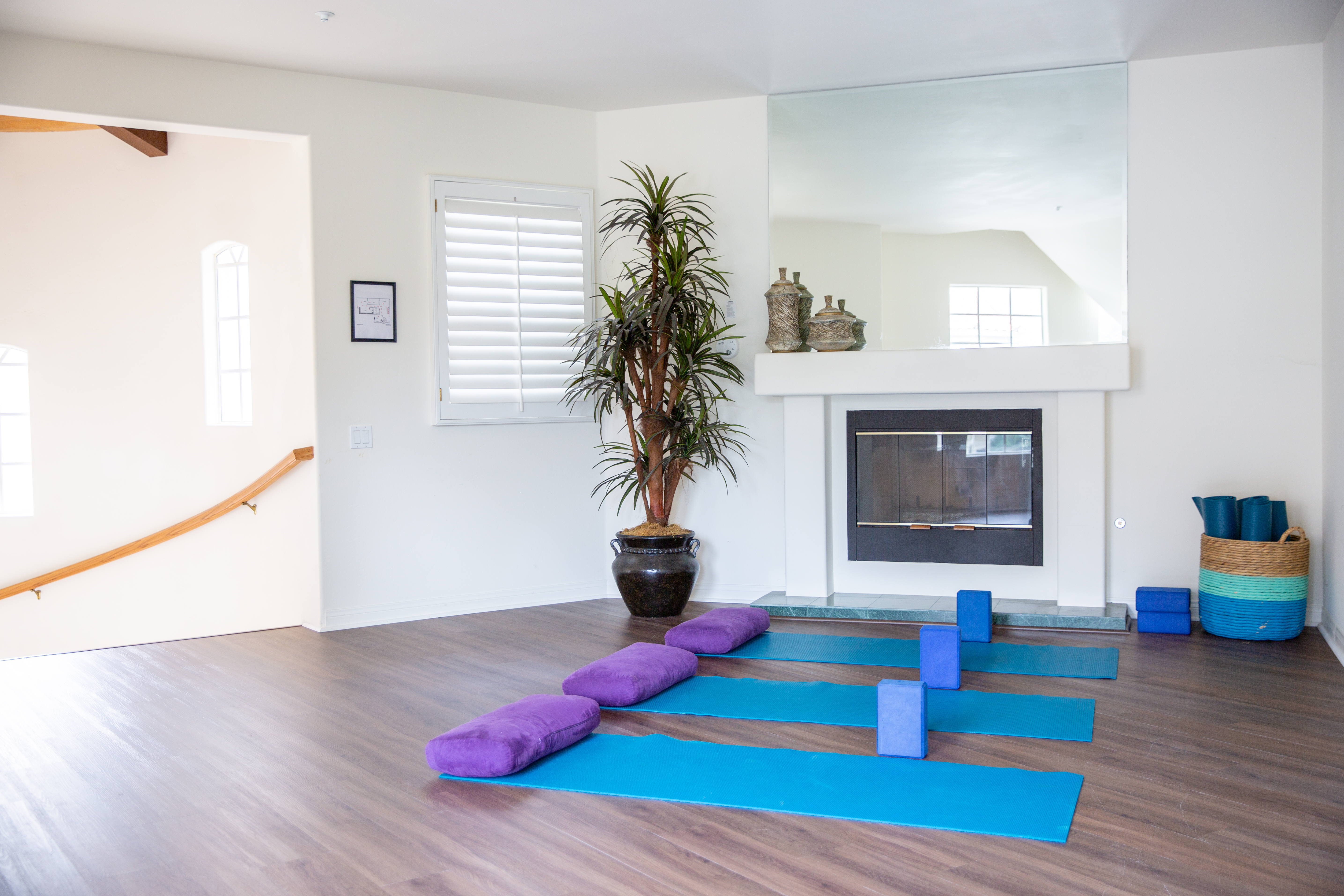 Open space with yoga mats, props, and a fireplace