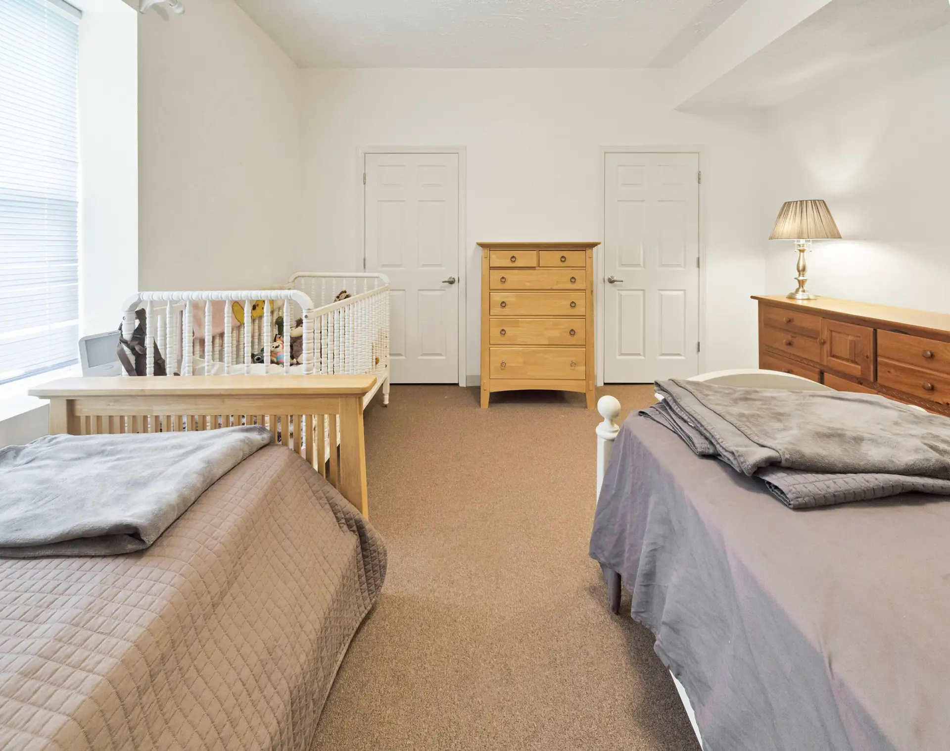 Residential bedroom with two beds, crib, and storage furniture
