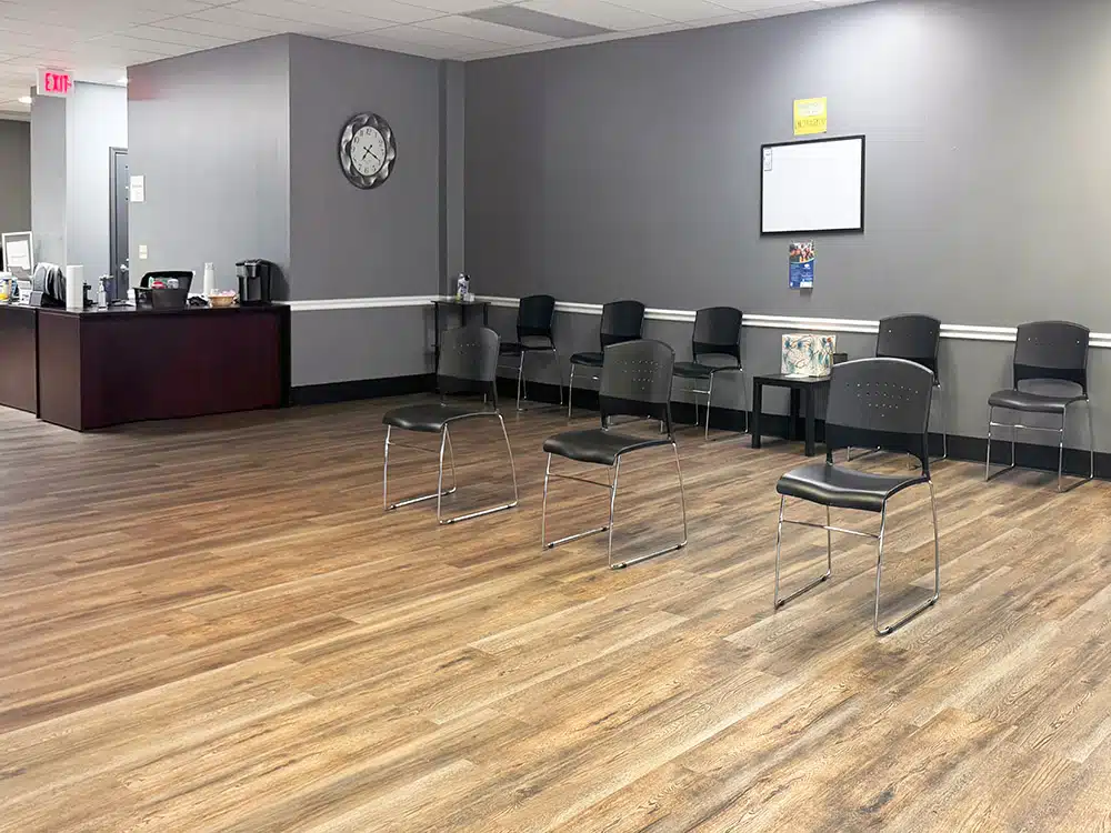 Group therapy room with spaced chairs and coffee station