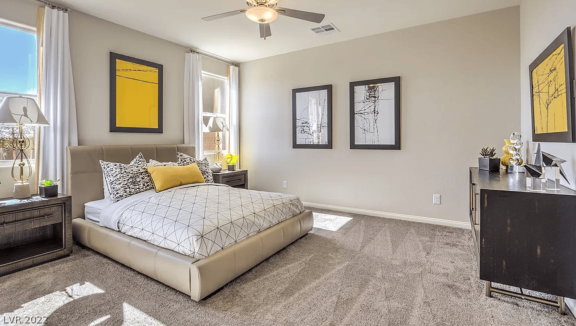 Bright furnished bedroom with upholstered bed, bedside tables, dresser, and contemporary artwork