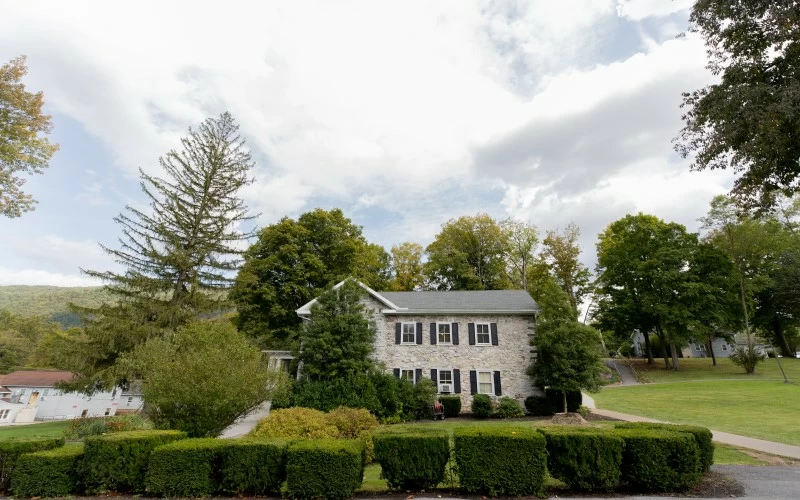 Stone facility building surrounded by trees and hedges