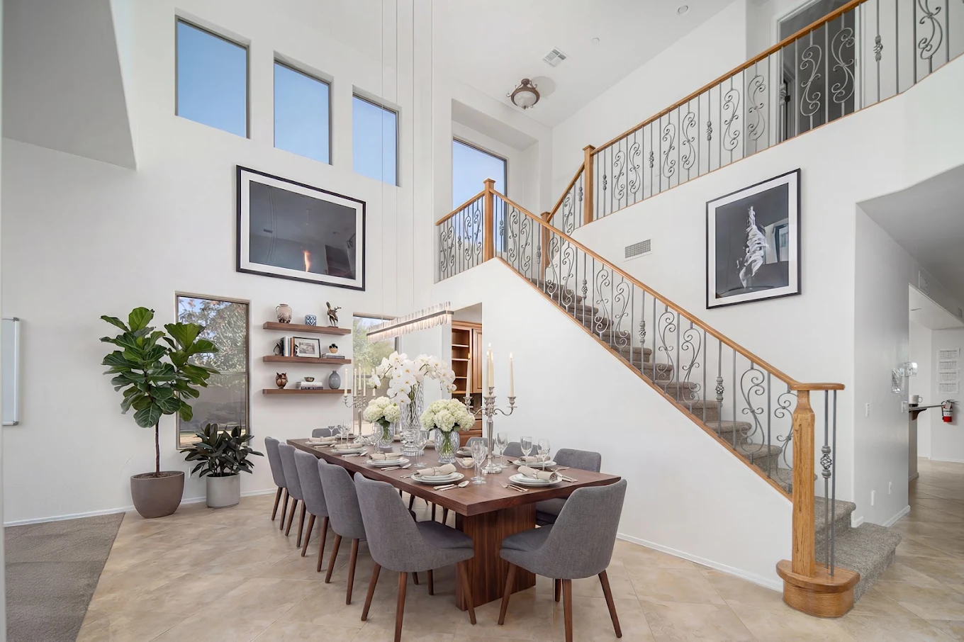 Bright dining area with large table, high ceilings, and staircase