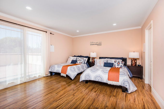A bedroom with two beds, soft lighting, and decorative pillows.