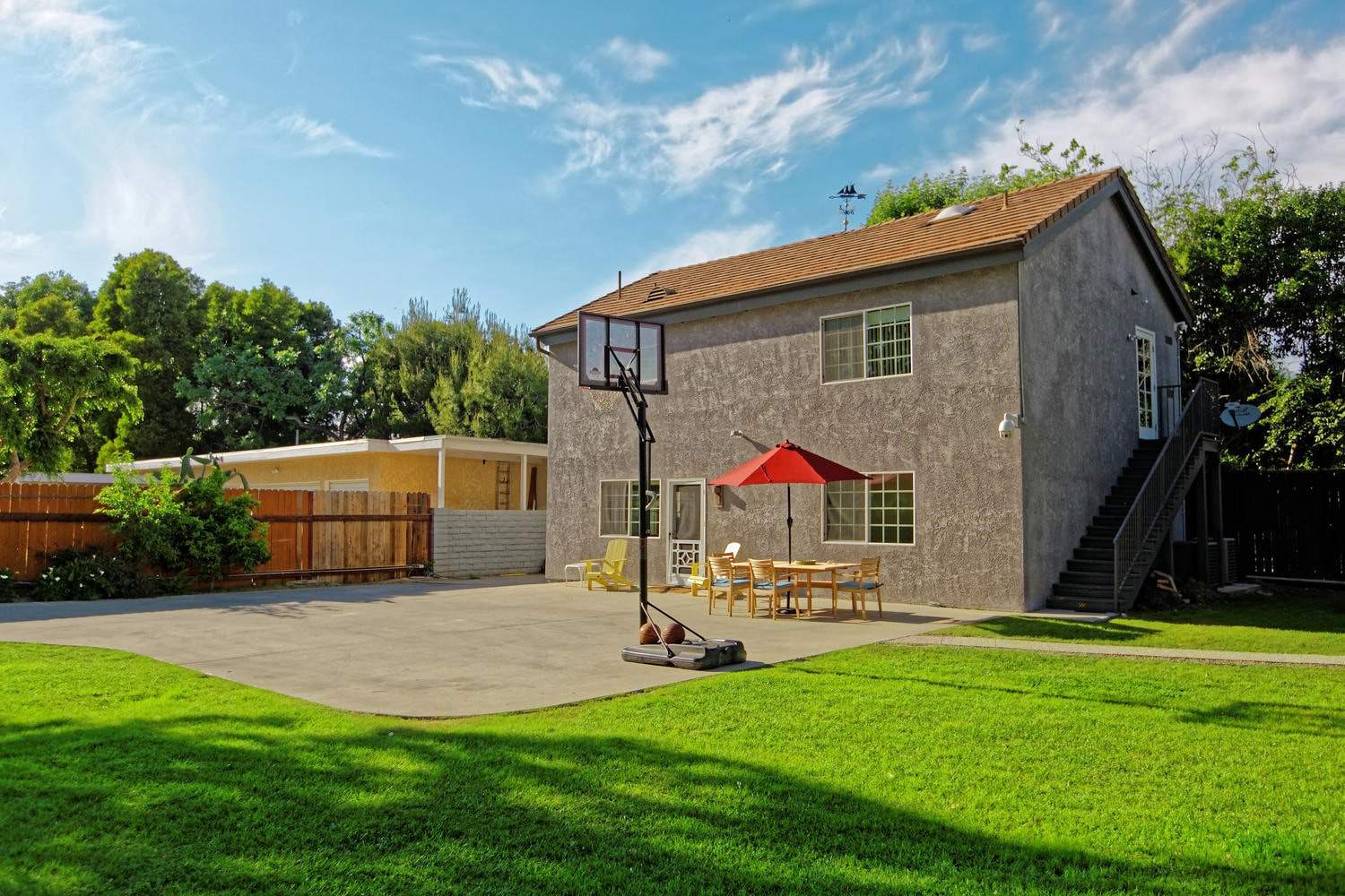 Outdoor basketball court with patio seating and umbrella